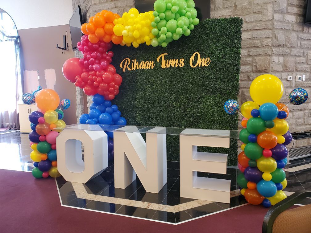 marquee table with a green boxwood wall and balloon decor